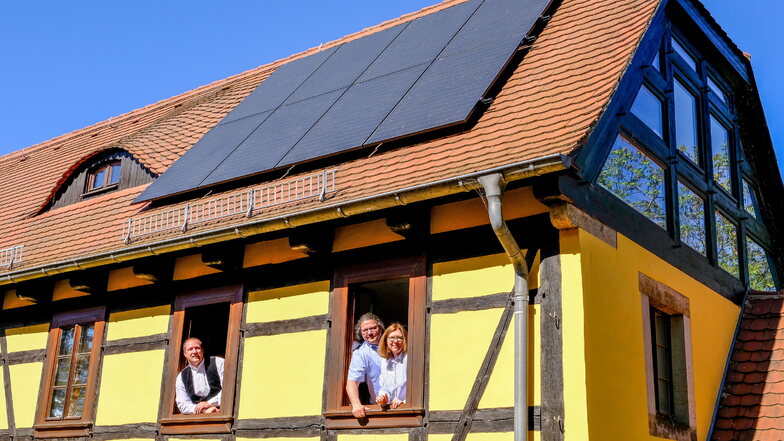 Neue Solaranlage im Familienzentrum Radebeul.  Ralf Burgold, Mathias Abraham und Annett Müller-Bühren (v. l. n. r.)  schauen aus den Fenstern des denkmalgeschützten Hauses. Über ihnen befinden sich Photovoltaikmodule.