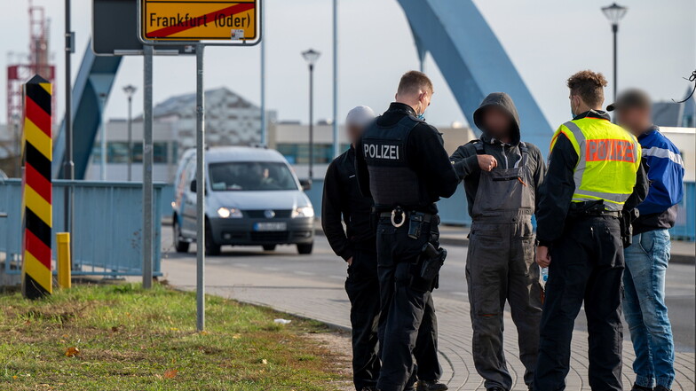 Zwei Polizisten kontrollieren auf der Grenzbrücke zwischen Deutschland und Polen drei Männer.