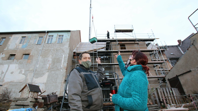 Die Eigentümer des Hauses am Markt 13 in Roßwein, Heike und Matthias Liebscher, verfolgen die Bauarbeiten. Die Dachdeckerfirma hatte am Dienstag einen 52 Meter großen Kran im Einsatz.