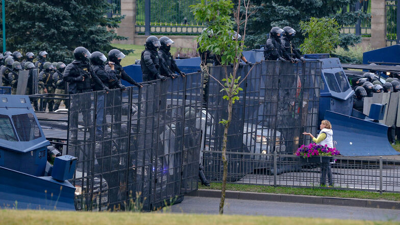 Eine Frau steht vor einer Barrikade von Bereitschaftspolizisten in Minsk.