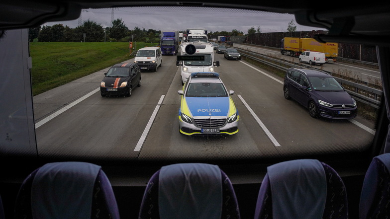 Die Autobahnpolizei folgt dem Bus mit einem Streifenwagen, um Lasterfahrer sofort zu stoppen, wenn sie zum Beispiel dabei beobachtet wurden, als sie während der Fahrt mit ihrem Handy beschäftigt waren.