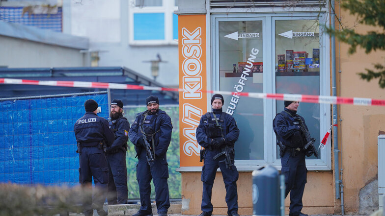 Einsatzkräfte der Polizei stehen vor einem der Tatorte, einem Kiosk in Hanau.