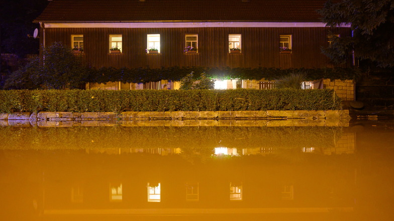 Eine Straße ist vor einem Wohnhaus in Bad Schandau mit Wasser der Kirnitzsch überflutet.