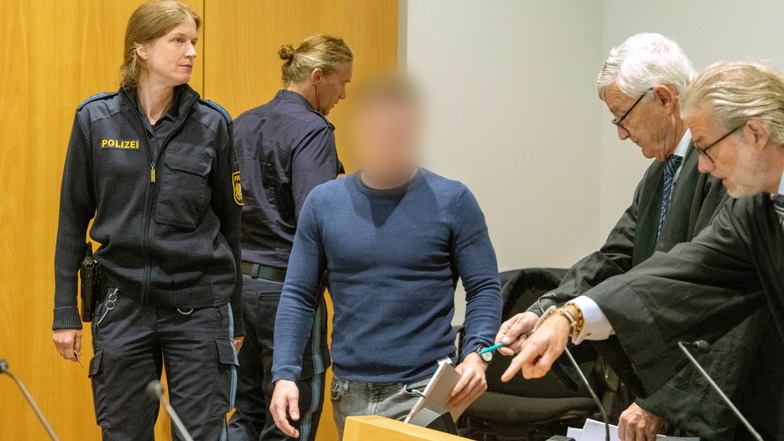 Augsburg: Im Strafjustizzentrum wird ein Mann von einer Polizistin in den Schwurgerichtssaal geführt, wo seine Anwälte warten. Der Angeklagte soll bei einem Raserunfall eine entgegenkommende Autofahrerin getötet haben.