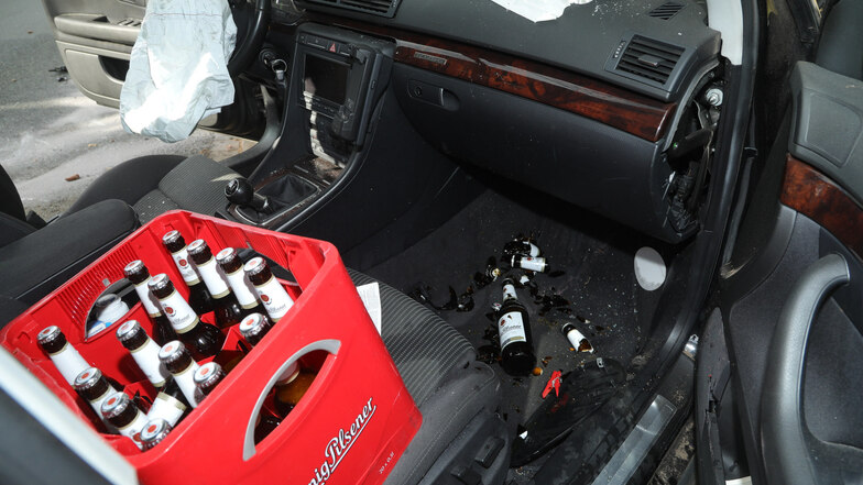 Ein Kasten Bier steht auf dem Beifahrersitz, im Fußraum liegen teils zerbrochene leere Flaschen.