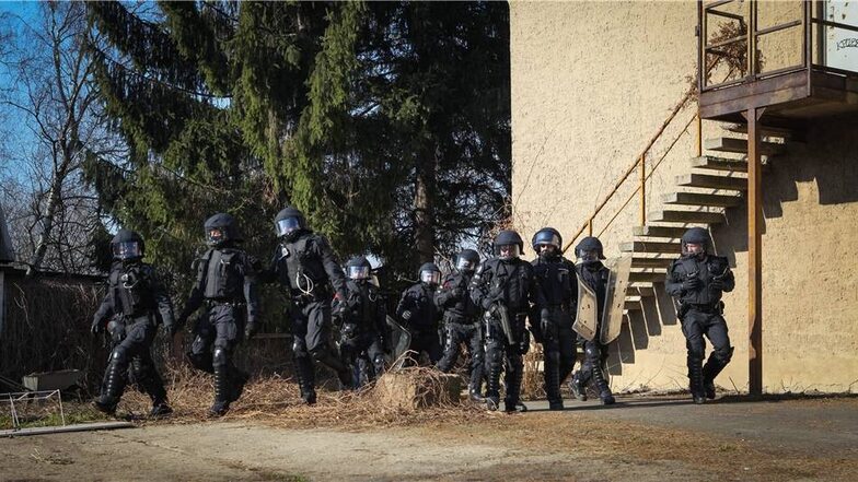 Martialisch uniformiert verschafft sich die Polizei Zutritt zum Gelände.