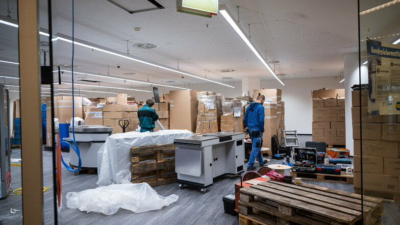 Die Ware ist verpackt in Kartons. Monteure bauen die neuen Regalsysteme auf.