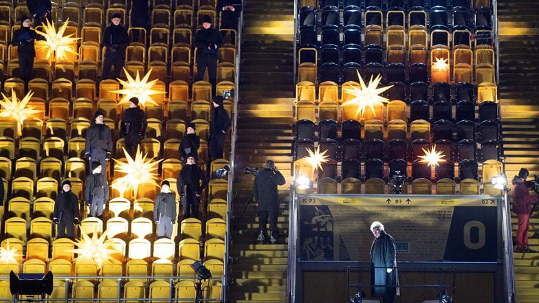 Auf Abstand: Mitglieder des Dresdner Kreuzchors stehen vor Beginn des Adventskonzerts im leeren Rudolf-Harbig-Stadion auf der Zuschauertribüne zwischen Herrnhuter Sternen.