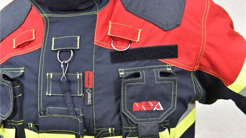 Zusatztaschen/Funktionen: Die Uniform verfügt über eine Menge von kleineren Taschen, in denen die Feuerwehrleute unter anderem Funkgeräte unterbringen können. In der Jackenmitte befinden sich zwei Schlaufen, in die man zum Beispiel eine Lampe einhängen kann.