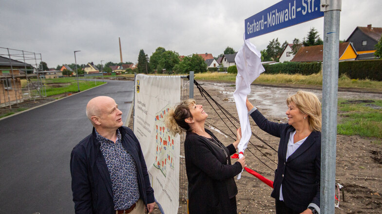 Ute Backemeier (re.) und ihre Tochter Madeleine Raschinski enthüllen das Schild mit dem Namen ihres Vaters und Opas. Die Wohngebietsstraße im neuen Wohngebiet ist nach dem Ehrenbürger und Ex-Bürgermeister von Bernsdorf benannt.