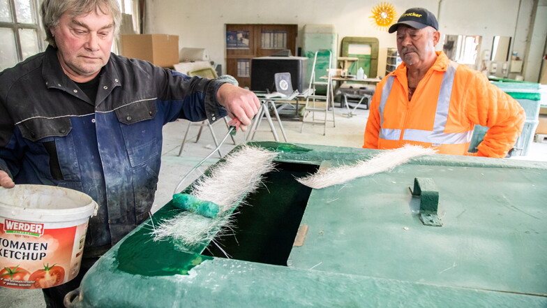 Mit fachkundigem Blick beobachtet Armin Kittner (rechts), wie sein Mitarbeiter Hartmut Jurke eine Glasfasermatte mit Harz einstreicht. Mit diesem Verfahren wird der Fischtransportbehälter repariert.