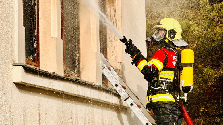 Von außen löscht ein Feuerwehrkamerad die Brandwohnung.