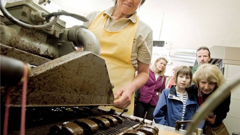 Monika Lindner zeigt in der Pfefferküchlerei Max Spitzer wie Pfefferkuchen mit Schokolade überzogen werden. Familie Schulze aus Dresden schaut genau zu, wie die Überzugmaschine funktioniert.