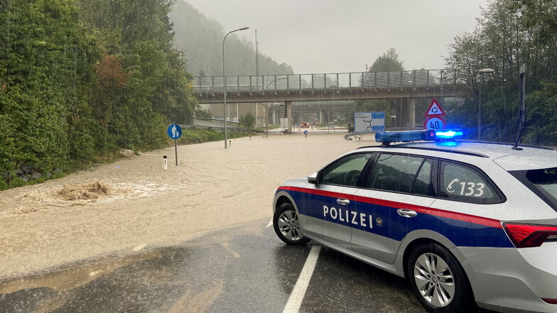 Ein Polizeifahrzeug steht nach Starkregen an einer überschwemmten Straße bei Wolfurt in der Nähe von Bregenz, Vorarlberg, Österreich.