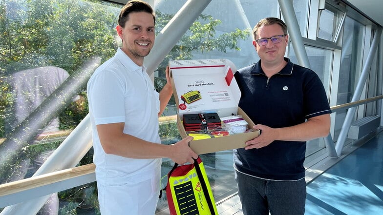 Marcel Damme und der Vorstand der Elblandkliniken, Rainer Zugehör, zeigen den Inhalt der Ersthelfertaschen.