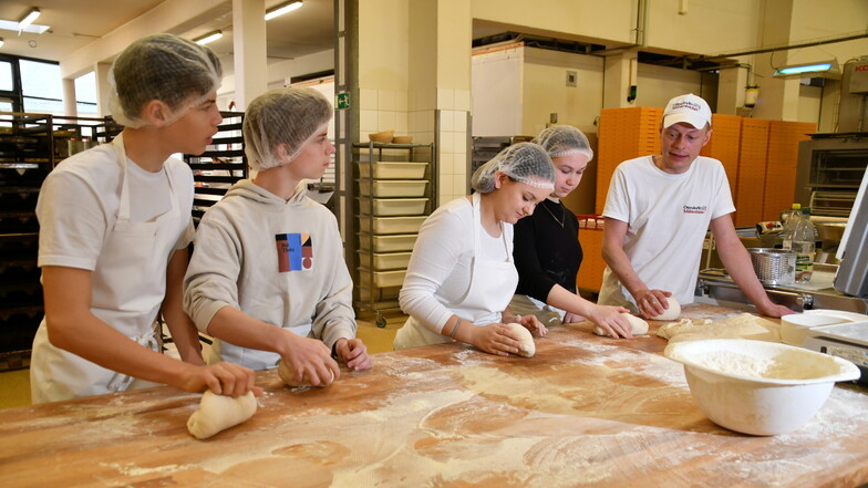 Bäckermeister Martin Rosenkranz (r.) erklärt Ilyan, Adrian, Finnja und Marla, wie man den Brotteig richtig knetet.