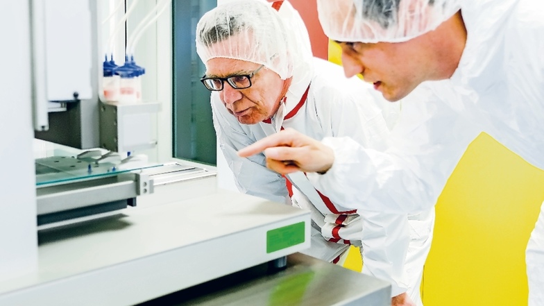 Thomas de Maizière (links) hat Bundesfördermittel mit nach Radebeul gebracht. Sascha Heinemann, Geschäftsführer von Innotere GmbH, erklärt ihm im Reinraum, wie Knochenersatz im 3-D-Drucker entsteht.