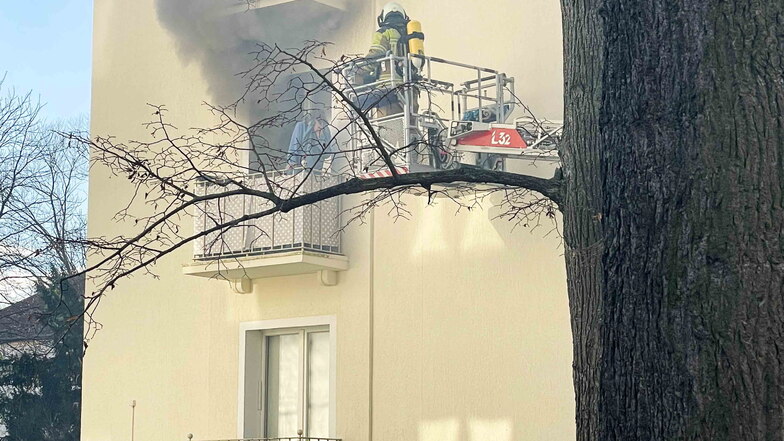 Ein Feuerwehrmann wird mit einer Drehleiter zu einer Anwohnerin gebracht, um sie vom Balkon ihrer brennenden Wohnung zu retten.