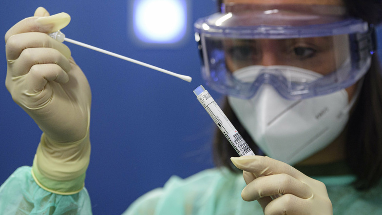 Eine Ärztin der Kassenärztlichen Vereinigung Sachsen hält in der Corona-Teststation für Urlaubsrückkehrer am Flughafen Dresden International eine Abstrich für einen Coronavirus-Test in den Händen.