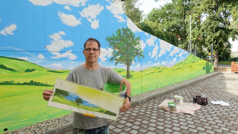 Der Graffiti-Künstler Frank Schäfer kann auch mit dem Pinsel. An der Stützmauer neben dem Neubau der GWG hat er eine Hügellandschaft entstehen lassen.