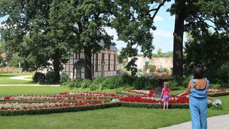 Im Vordergrund Blumenpracht, dahinter der Nachbau des einstigen Schönwaldauer Bethauses – beides zieht die Blicke der Menschen auf sich. Zu sehen ist das im Park von Schloss Lomnica (Lomnitz) im Hirschberger Tal in Polen.
