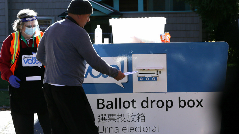 Eine Mitarbeiterin von King County Elections assistiert einen Wähler an einer Wahlurne in der Beacon Hill Library im Bundesstaat Washington.