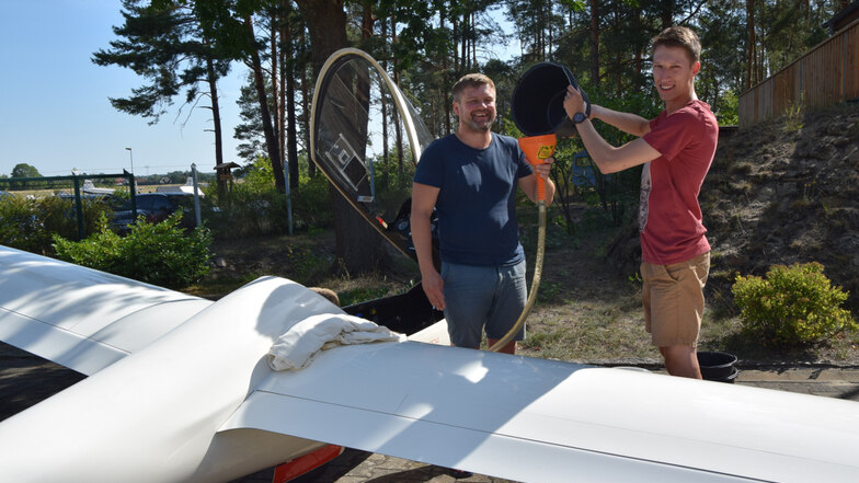 Benjamin Pichl (links) und Tobias Thaler füllen Wasser in die Flügeltanks eines Segelflugzeuges, um damit dessen Gleitgeschwindigkeit zu erhöhen.