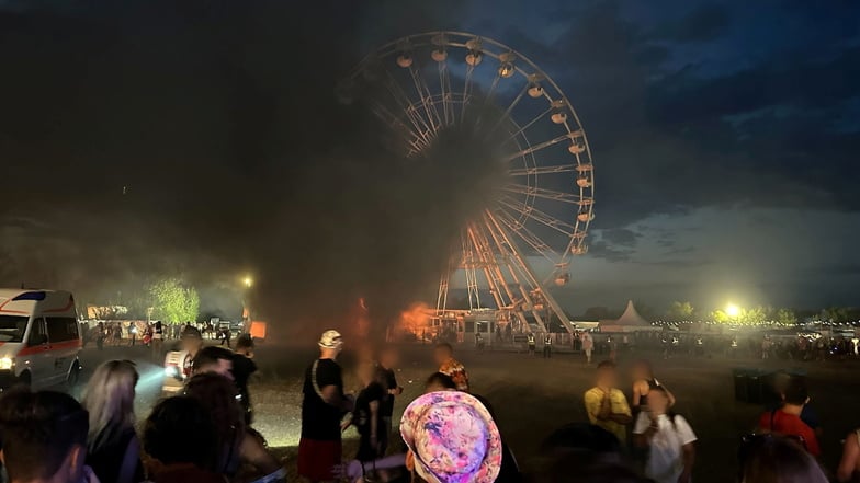 Besucher des Highfield-Festivals bei Leipzig blicken auf ein Riesenrad, an dem Flammen zu sehen sind.