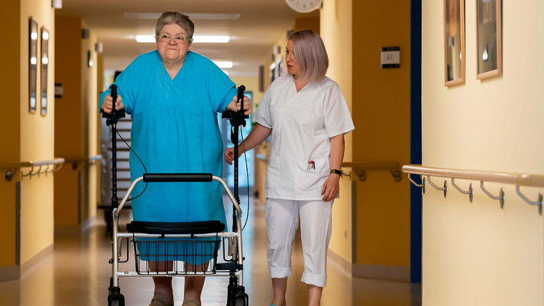 Trotz Rollator fällt Brigitte Weigelt das Laufen noch schwer. Schwester Lysann Dökert unterstützt sie auf dem Gang der Chirurgischen Klinik im Krankenhaus Bischofswerda.