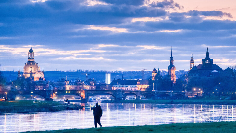 Ein Mann spaziert allein an der Elbe in Dresden.