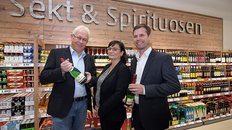 Uwe Krause von Penny, Claudia Hoyer und Dirk Förster-Wehle von der TAG Wohnen stehen im großzügig dimensionierten Markt vor dem modern gestalteten Bereich für Spirituosen.