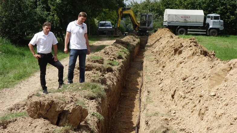 In Richtung Mochau werden die Kabel in der Erde verlegt. Stadtwerkechef Gunnar Fehnle und Netzmeister Mirko Lößner stehen bei Oberranschütz an einem offenen Kabelgraben.