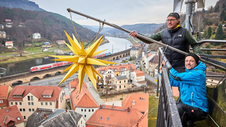Bis Anfang Februar leuchtet der Herrnhuter Stern auf dem Turm der Königsteiner Stadtkirche: Ricco Dunsch und Torsten Jackl (re.) haben ihn am Wochenende befestigt.
