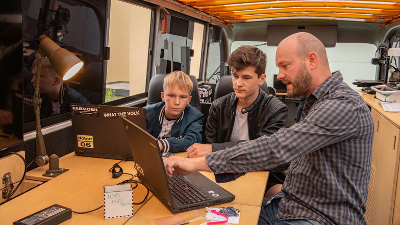 Mitarbeiter Julius Plüschke (r.) zeigt Phil Weitland und Florian Konschak die Programmierung des Designs.