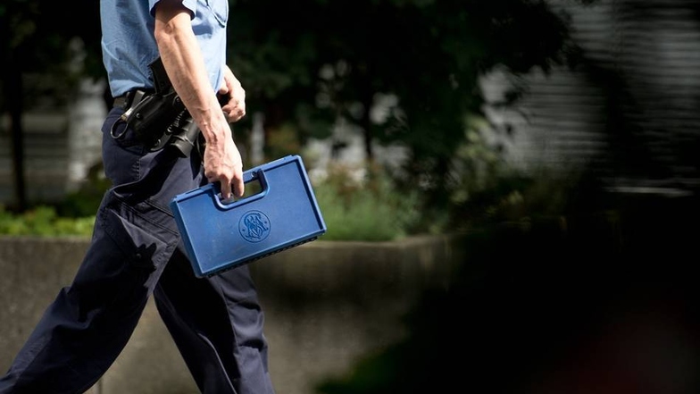 Ein Polizist trägt einen Koffer mit dem Logo des Waffenherstellers Smith & Wesson in das Verwaltungsgebäude von Siemens.