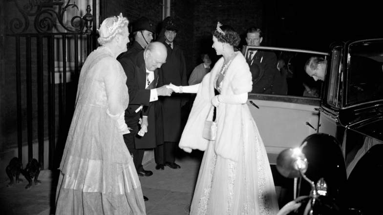 1955 verbeugt sich Winston Churchill neben seiner Frau vor der Queen. Churchill war der erste von 15 Premierministern- und ministerinnen, die Elizabeth II. in ihrer Amtszeit erlebte.