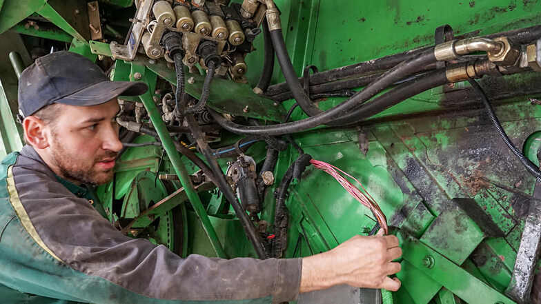 Ein Mitarbeiter der Porst Landtechnik GmbH repariert einen Mähdrescher.