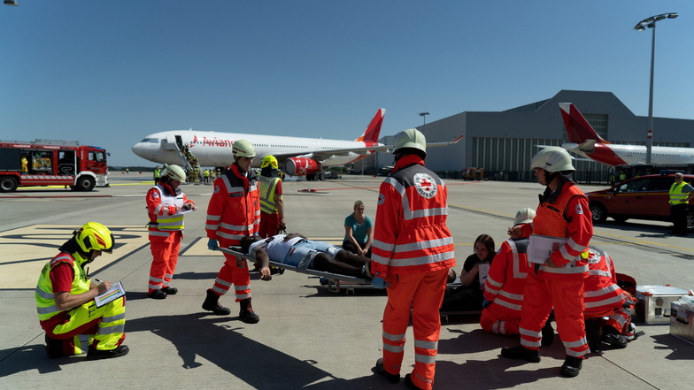 Rettungskräfte tragen eine Bahre auf dem Rollfeld des Dresdner Flughafens.