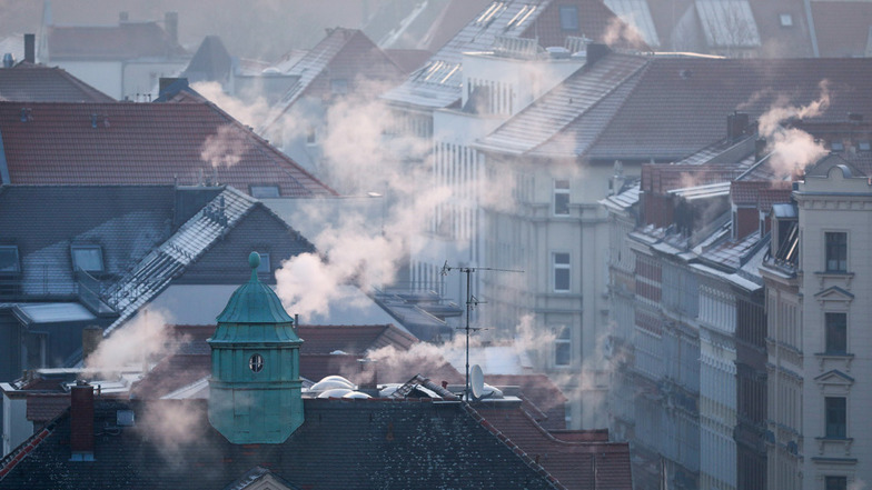 Rauch strömt aus den Kaminen auf den Dächern der Mehrfamilienhäuser im Leipziger Süden an einem kalten Wintermorgen. Die Treibhausgas-Emissionen in Deutschland sind im vergangenen Jahr nach ersten amtlichen Berechnungen deutlich zurückgegangen.