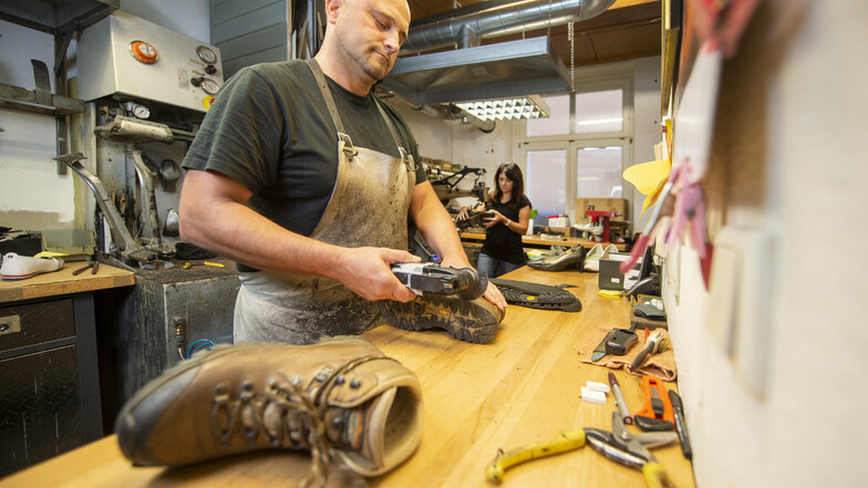 Schuhmacher Marcus Lange repariert Wanderschuhe in seiner Werkstatt in der Breite Straße 22 in Pirna. Im Hintergrund steht Mitarbeiterin Grit Rieger.