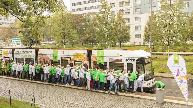 20 Landwirte, 20 Bäcker und Verterter der Dresdener Mühle schieben die neue Straßenbahn an.