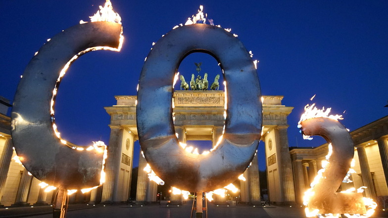 Bei einer Greenpeace-Aktion steht ein CO-2 Schriftzug vor dem Brandenburger Tor in Berlin, aus dem Flammen schlagen.