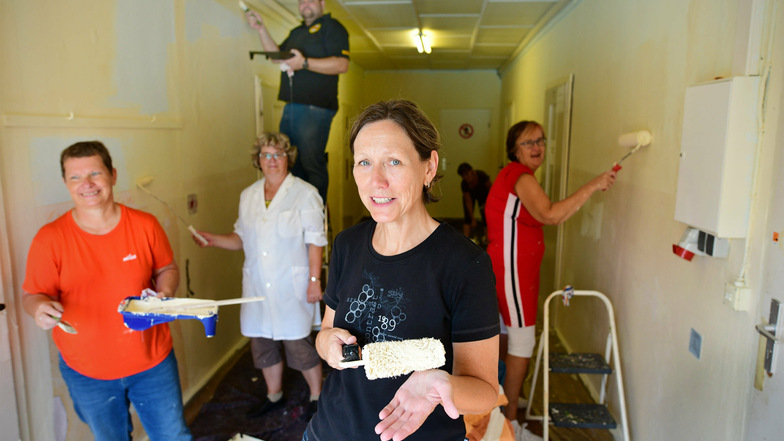 Christine Rohmann (Mitte) und ihre Kollegen von der Deutschen Post verschönern mit Pinsel und Farbe den Eingangsbereich des Gebäudes des Ostritzer Mewa-Bades.