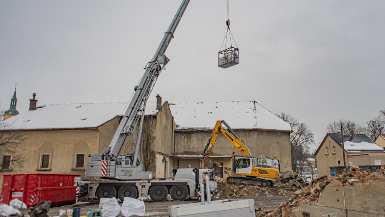 Der Abriss der Kante in Pulsnitz ist gestartet. Mit einem Kran werden Bauleute an das Gebäude gebracht.