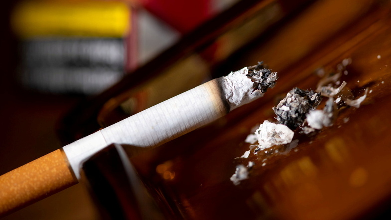 Eine brennende Zigarette liegt in einem Aschenbecher. In Deutschland werden weniger Zigaretten geraucht, der Konsum von Shisha-Wasserpfeifentabak steigt aber weiter deutlich. Und beim Alkohol bleibt Deutschland ein "Hochkonsumland",