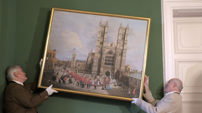 Das Geburtstagskind Roland Schwenke (r.) und Georg Prinz zur Lippe hängen die neue Canaletto-Replik auf, sie zeigt die Westminster Abbey in London.