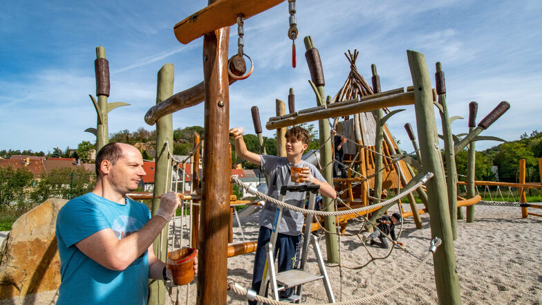 Mitglieder des Vereins Osiris, hier Jens Gießmann und Tim Janke (von links), streichen die Spielgeräte auf dem Spielplatz "Rösser im Schilf" in Roßwein