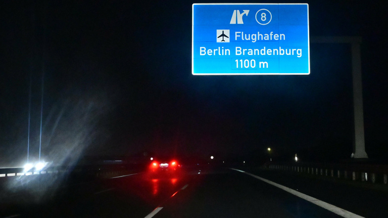 Im Licht der Autoscheinwerfer leuchtet am frühen Samstagmorgen ein Hinweisschild für eine Autobahnabfahrt zum Flughafen Berlin Brandenburg. 