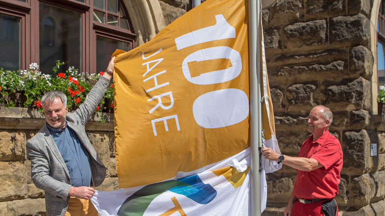 Oberbürgermeister Uwe Rumberg (links) und Hausmeister Hans-Joachim Huth hissen die neue Flagge.