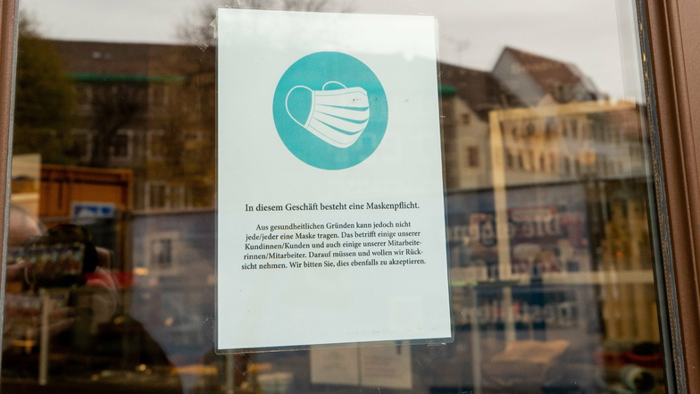 An einem Schaufenster einer Bäckerei in Pirna hängt ein Schild, das Kunden auf das Tragen der Alltagsmasken hinweist.